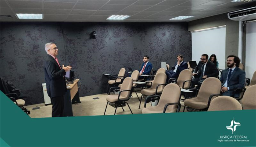 Homem em pé fala para pessoas sentadas em cadeiras