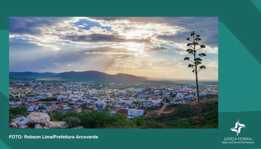 Foto com fundo verde, mostra a cidade de Arcoverde ao longe, com o por do sol de fundo