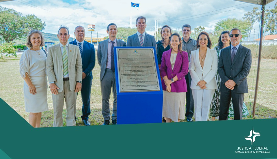 Foto com fundo verde e pessoas em pé atrás de uma placa