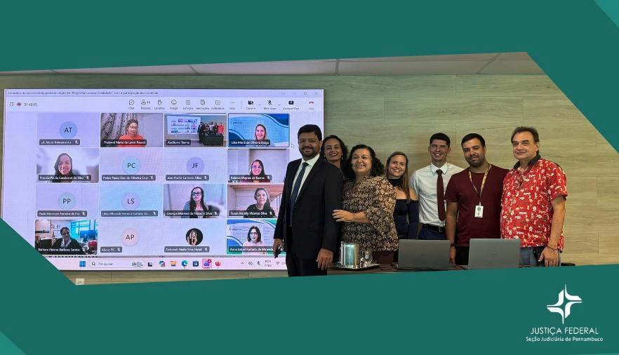 Mostra pessoas em pé e uma tela de computador
