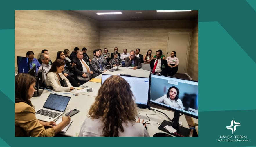 Foto com fundo verde, mostra pessoas sentadas em uma sala